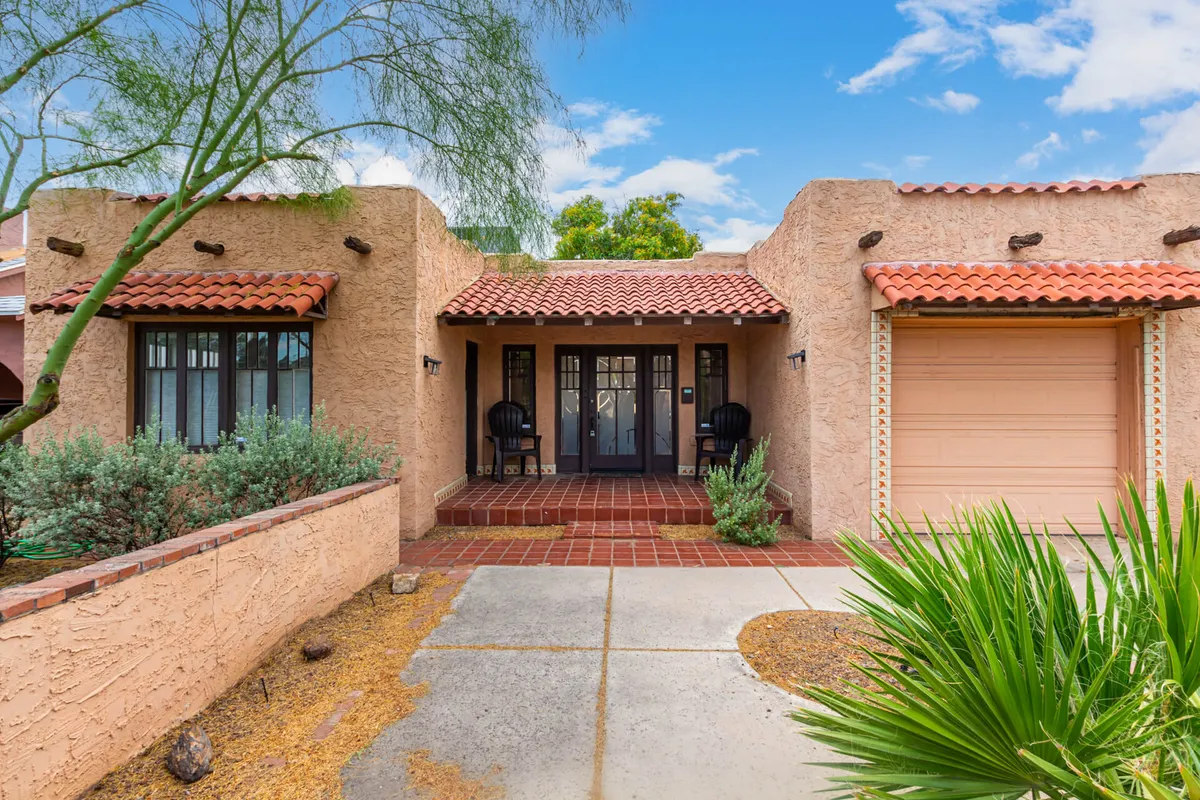 This image captures the front entrance of the property with a red tile roof and welcoming outdoor seating. The porch is set against a backdrop of well-maintained landscaping, suggesting a pleasant and approachable neighborhood environment.