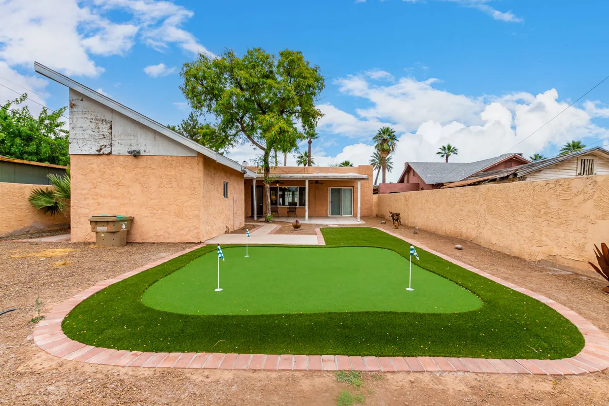 This image spotlights an artificial putting green surrounded by green grass and palm trees, set in a desert landscape. The area invites outdoor activities and social gatherings, ideal for long-term guests seeking both recreation and community.